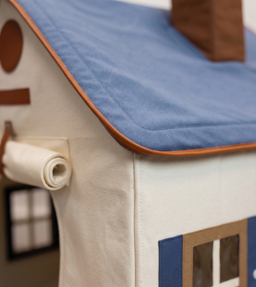 Close-up of a fabric dog house model with blue roof and brown accents.